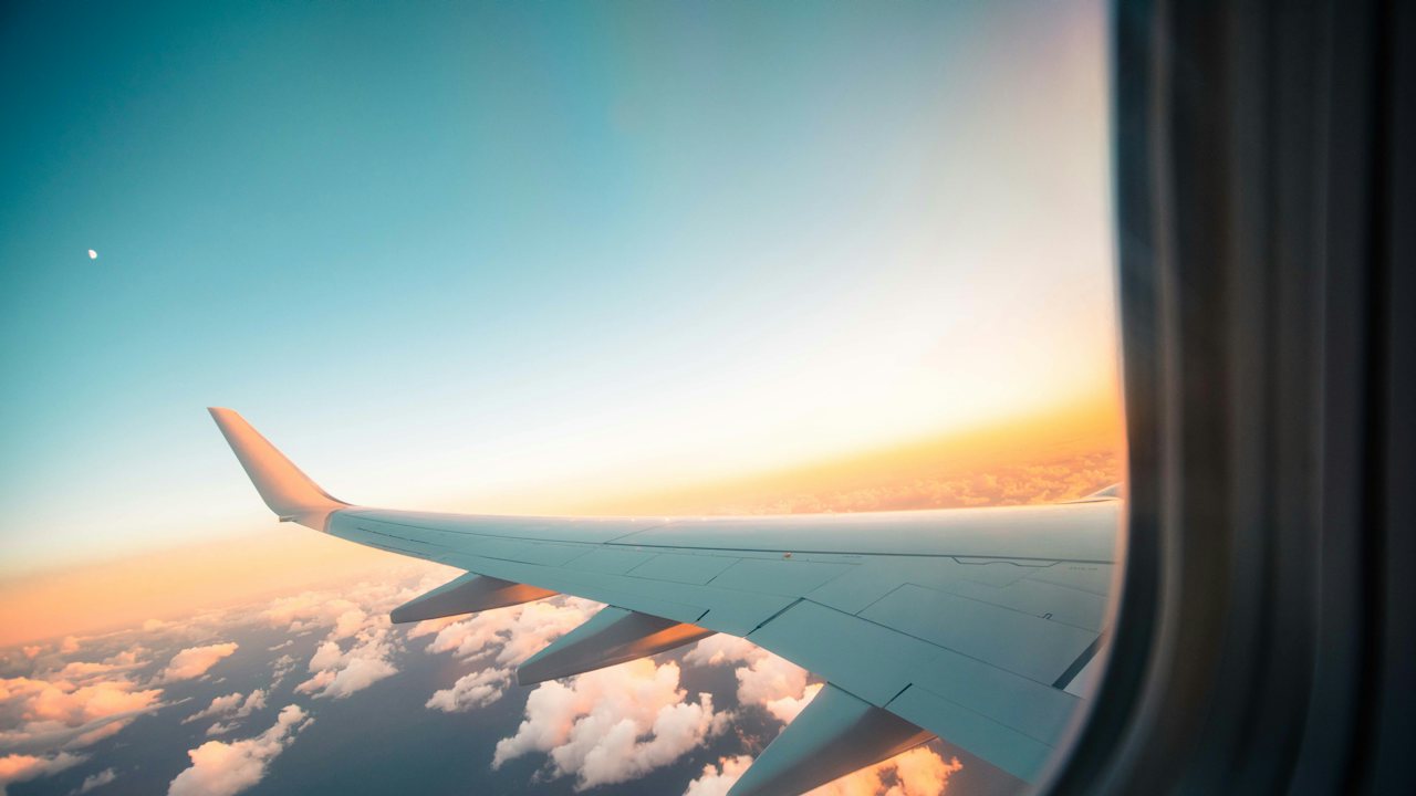 Aircraft wing above the clouds at sunset, seen from the cabin window