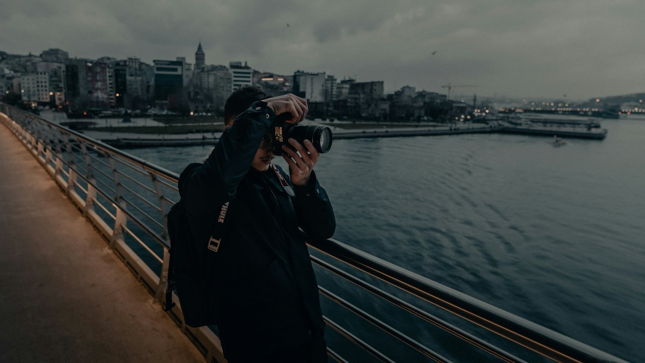 Photographer with a camera on a waterfront walkway in Istanbul, Galata Tower behind