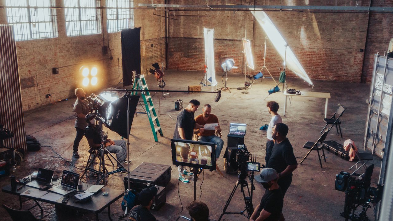 Film crew working around cameras, monitors and lights in a warehouse studio
