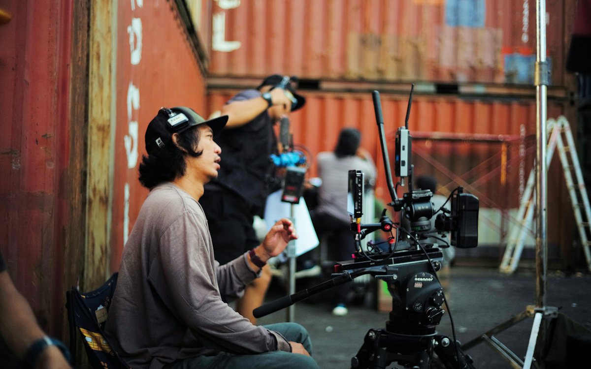 Crew gathered around monitors and a camera on an outdoor set